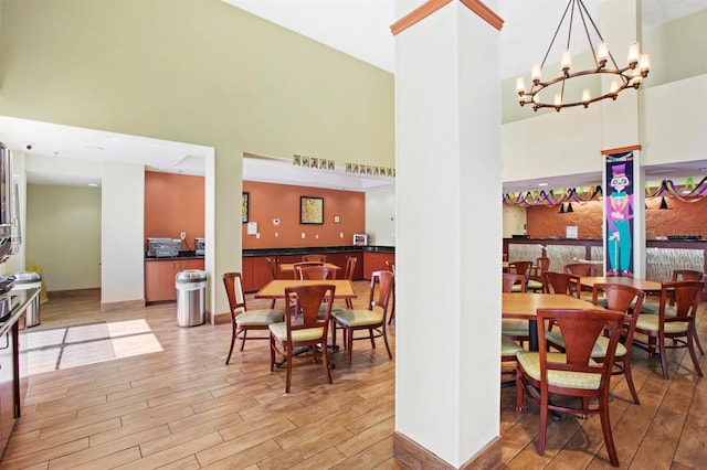 dining area featuring light hardwood / wood-style flooring, a notable chandelier, and a towering ceiling