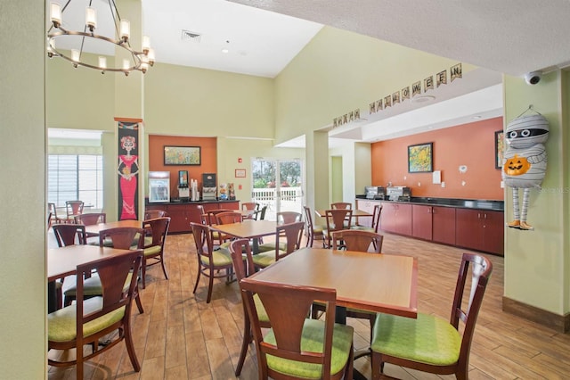 dining area with a towering ceiling, a chandelier, wood-type flooring, and plenty of natural light