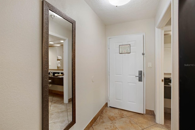 hallway featuring a textured ceiling and light tile patterned floors