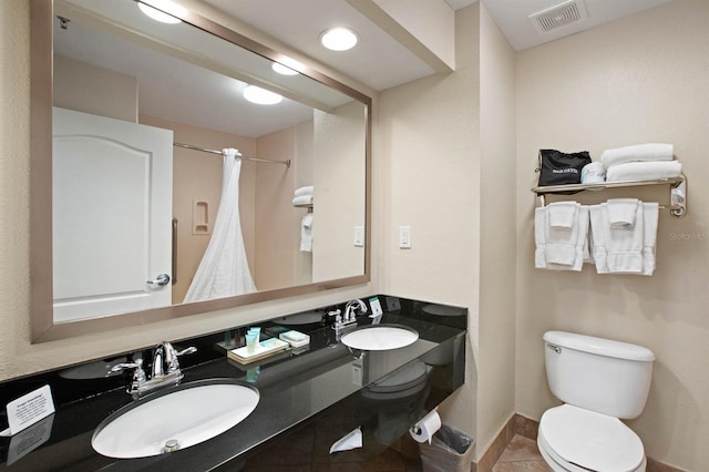 bathroom with toilet, walk in shower, vanity, and tile patterned flooring