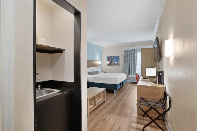 bedroom featuring sink, crown molding, and light hardwood / wood-style floors