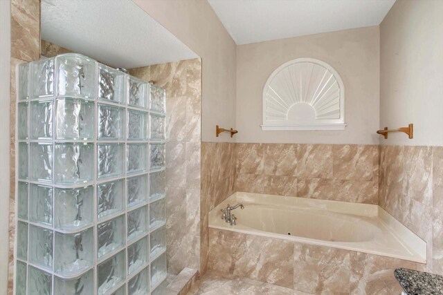 bathroom featuring shower with separate bathtub and tile walls