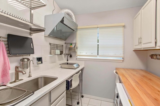 kitchen featuring white cabinetry, light tile patterned floors, sink, and wooden counters