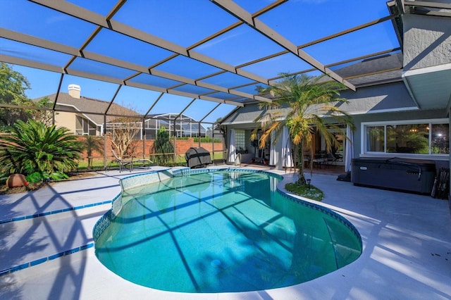 view of swimming pool featuring a hot tub, a patio area, and a lanai