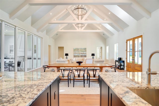 kitchen featuring french doors, light stone countertops, high vaulted ceiling, and sink