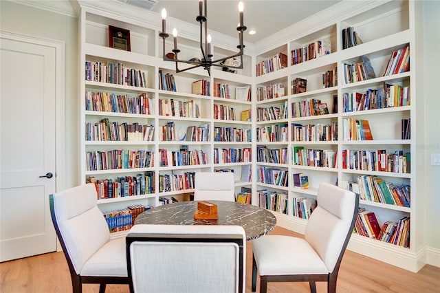 sitting room with crown molding, wood-type flooring, and a chandelier