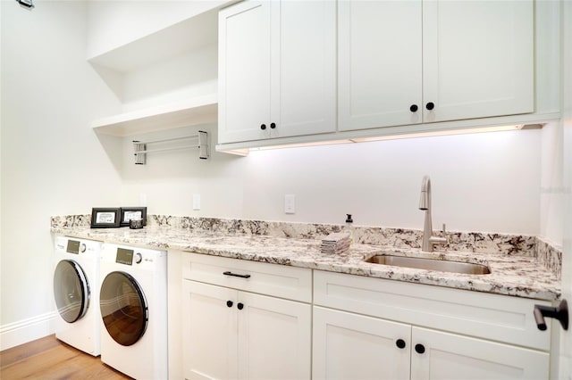 laundry room featuring cabinets, light hardwood / wood-style flooring, sink, and washing machine and clothes dryer