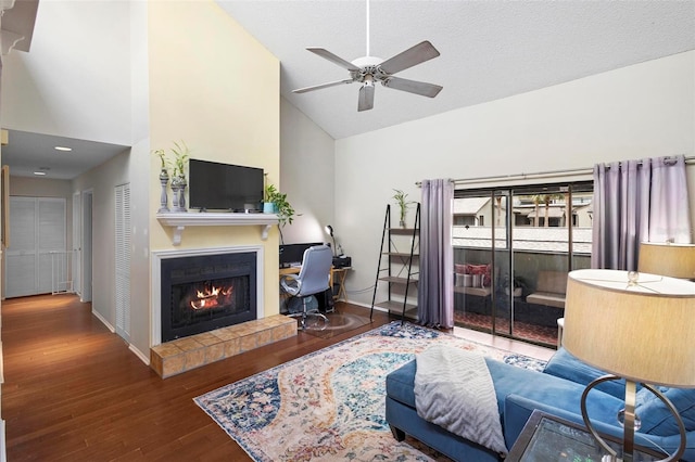 living room with a tiled fireplace, ceiling fan, a textured ceiling, high vaulted ceiling, and dark hardwood / wood-style floors