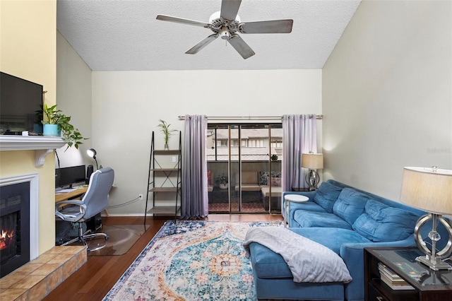 living room featuring lofted ceiling, a tiled fireplace, ceiling fan, a textured ceiling, and dark hardwood / wood-style floors