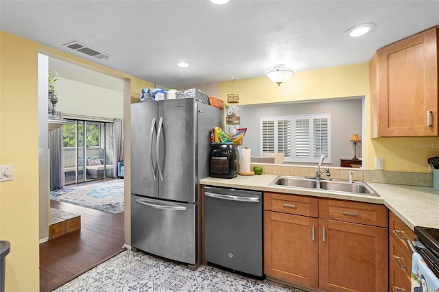 kitchen with appliances with stainless steel finishes, sink, and light hardwood / wood-style floors