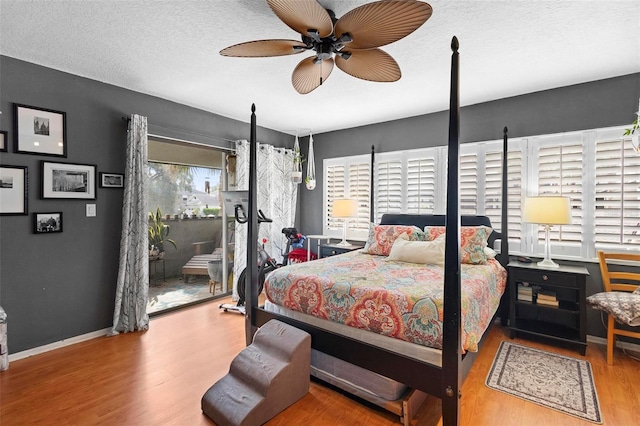 bedroom with access to outside, ceiling fan, wood-type flooring, and a textured ceiling