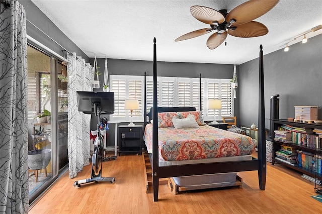 bedroom with ceiling fan, wood-type flooring, a textured ceiling, and track lighting