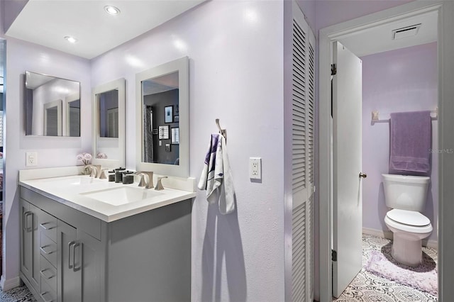 bathroom with toilet, vanity, and tile patterned floors