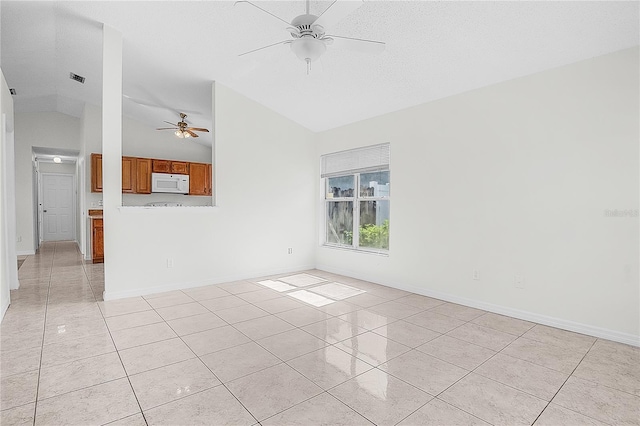 spare room with ceiling fan, vaulted ceiling, light tile patterned flooring, and a textured ceiling