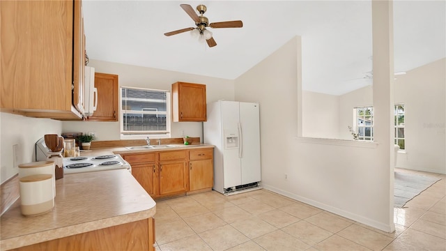 kitchen featuring a sink, white fridge with ice dispenser, a ceiling fan, and vaulted ceiling