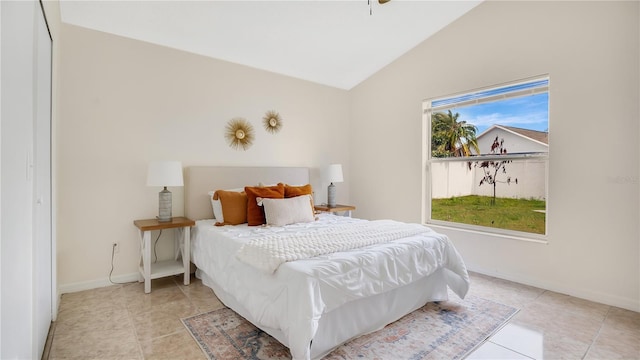 bedroom with lofted ceiling, light tile patterned floors, and baseboards