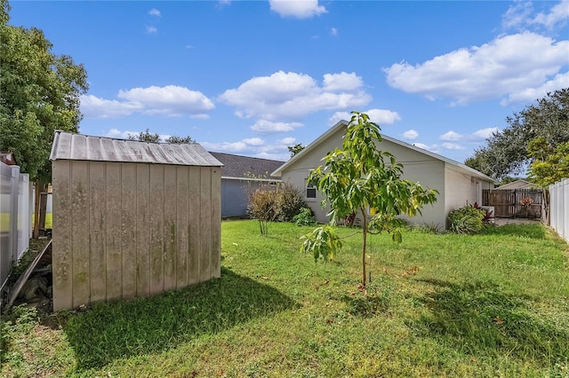 rear view of property with an outbuilding, a lawn, a fenced backyard, and a storage shed