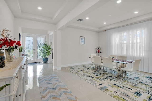 tiled dining area featuring a tray ceiling and french doors