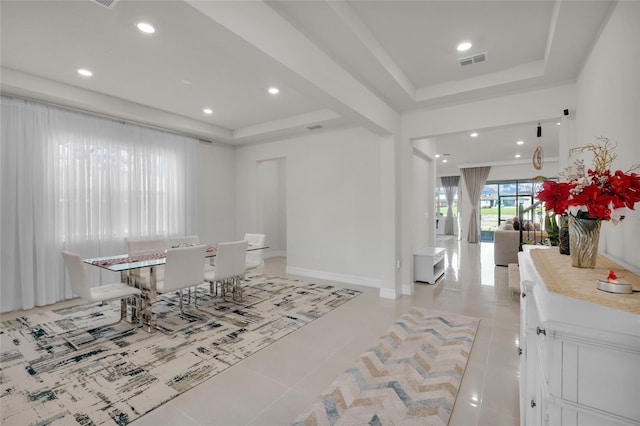 dining room featuring a tray ceiling and light tile patterned floors