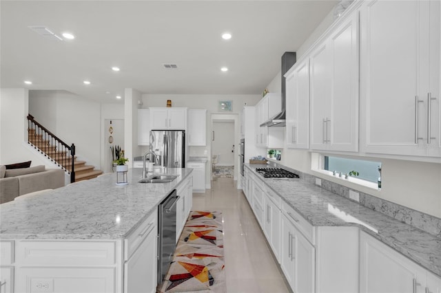 kitchen featuring appliances with stainless steel finishes, white cabinets, sink, and a large island with sink