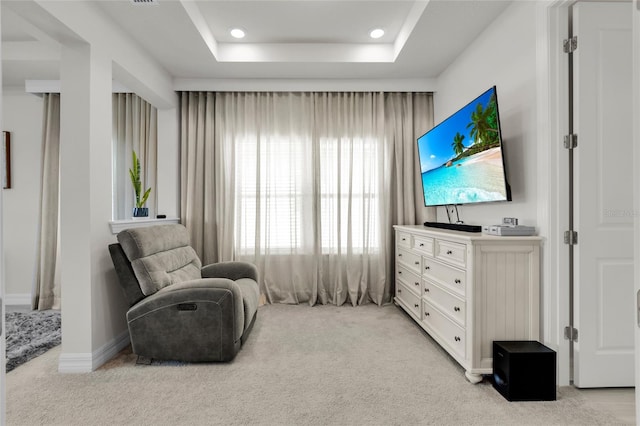 sitting room featuring light colored carpet and a tray ceiling