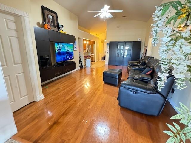 living room with lofted ceiling, hardwood / wood-style floors, and ceiling fan