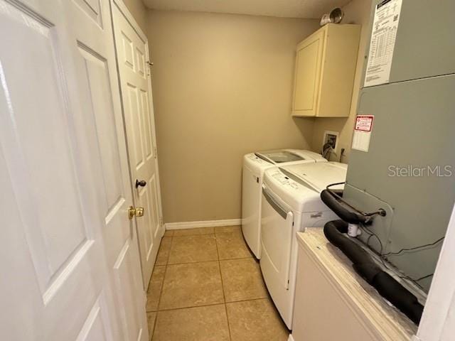 clothes washing area with cabinets, heating unit, washing machine and dryer, and light tile patterned floors