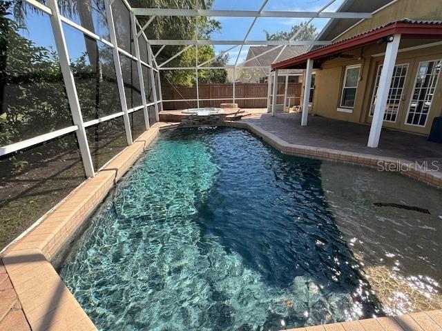 view of pool featuring an in ground hot tub, a patio, and glass enclosure