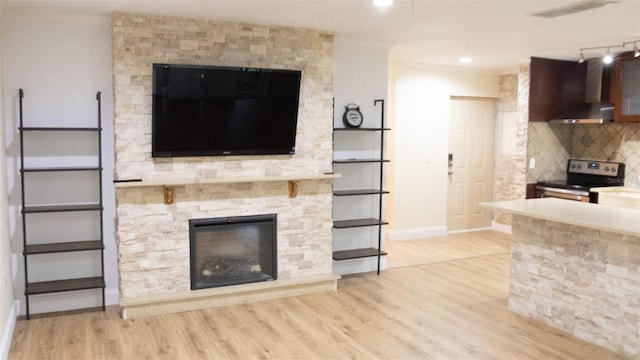 unfurnished living room with light hardwood / wood-style flooring, ornamental molding, and a fireplace