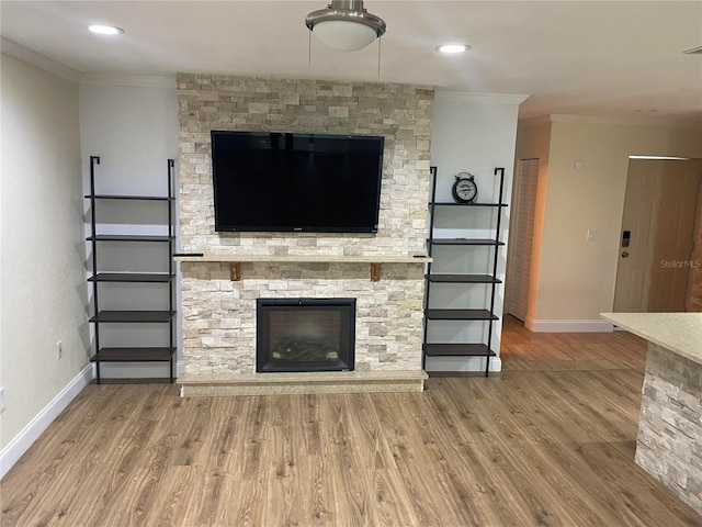 unfurnished living room featuring ornamental molding, hardwood / wood-style floors, and a stone fireplace