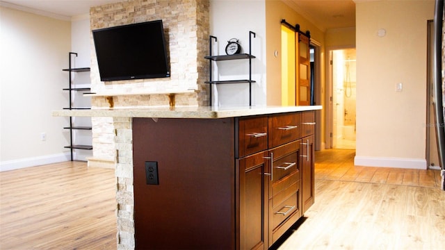 interior space with light hardwood / wood-style flooring, ornamental molding, and a barn door