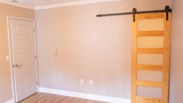 interior space featuring crown molding, a barn door, and light wood-type flooring