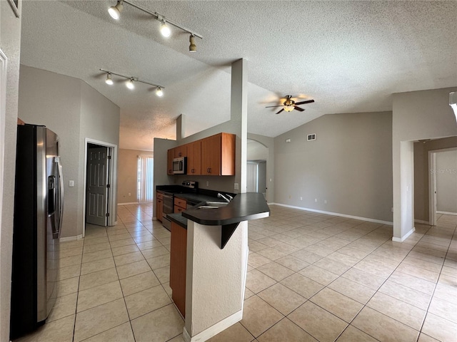 kitchen featuring ceiling fan, kitchen peninsula, lofted ceiling, a breakfast bar, and appliances with stainless steel finishes