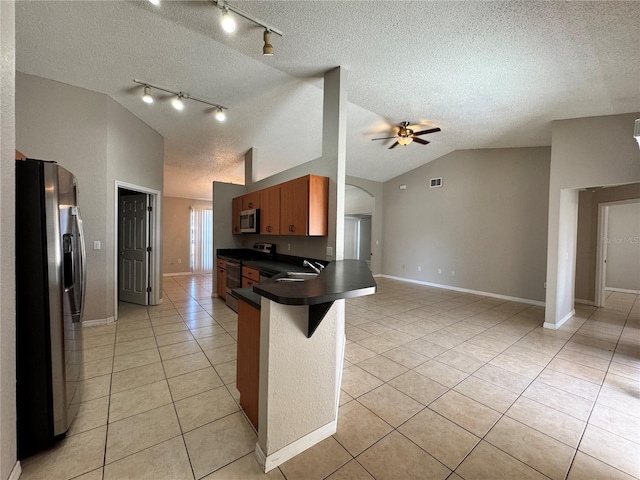 kitchen featuring a breakfast bar, lofted ceiling, a textured ceiling, appliances with stainless steel finishes, and kitchen peninsula