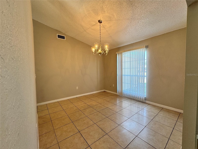 spare room with light tile patterned flooring, a textured ceiling, and a chandelier