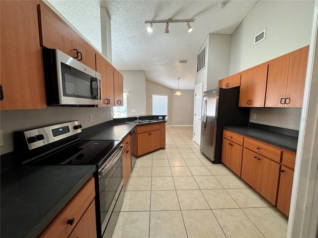 kitchen with stainless steel appliances, decorative light fixtures, track lighting, a textured ceiling, and light tile patterned floors