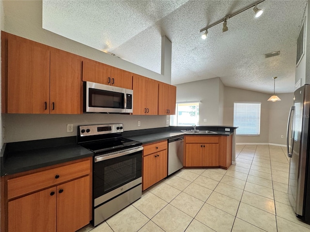 kitchen featuring lofted ceiling, track lighting, light tile patterned floors, a textured ceiling, and appliances with stainless steel finishes