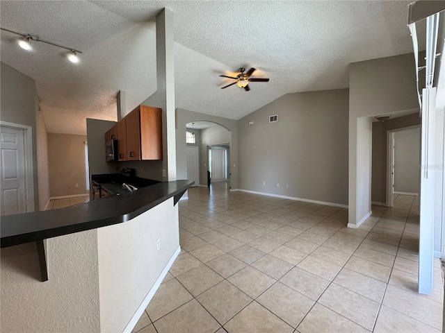 kitchen with kitchen peninsula, a textured ceiling, vaulted ceiling, and ceiling fan