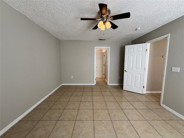 unfurnished bedroom with ceiling fan, light tile patterned flooring, a spacious closet, and a textured ceiling