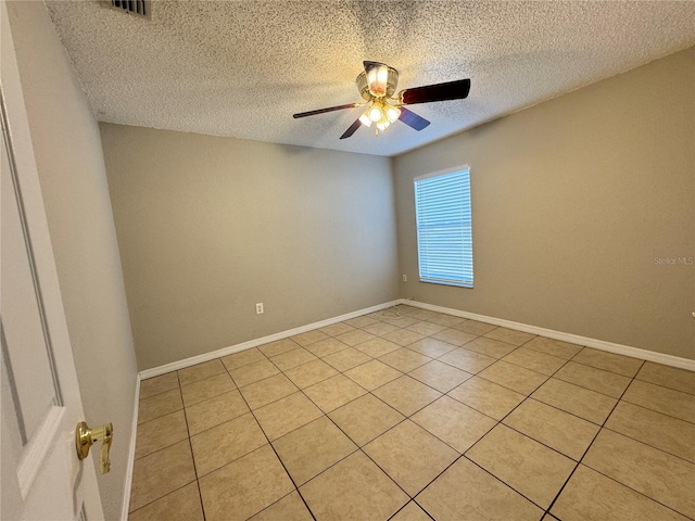 tiled empty room with ceiling fan and a textured ceiling