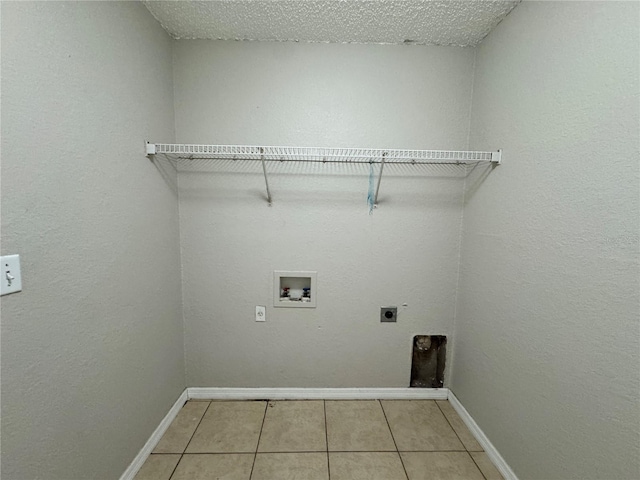 laundry room featuring electric dryer hookup, hookup for a washing machine, light tile patterned floors, and a textured ceiling