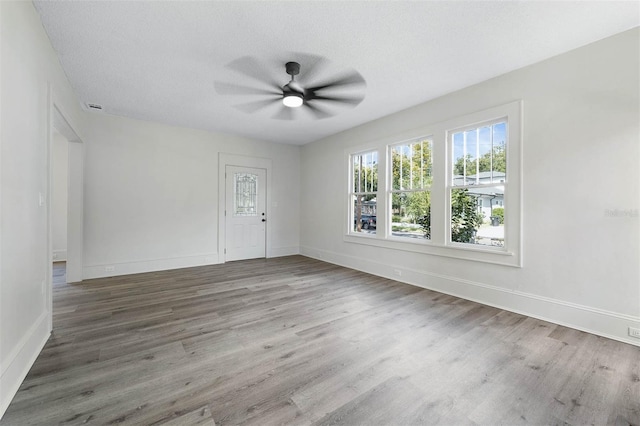 unfurnished room featuring ceiling fan, wood-type flooring, and a textured ceiling