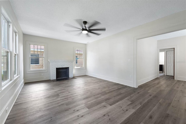 unfurnished living room with dark hardwood / wood-style floors, ceiling fan, a textured ceiling, and a brick fireplace