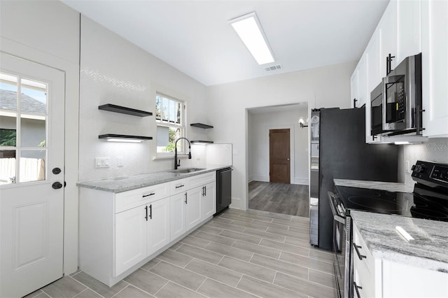 kitchen with appliances with stainless steel finishes, white cabinets, light stone countertops, and sink