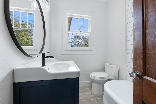 bathroom with a wealth of natural light, vanity, toilet, and a washtub