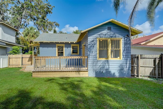 rear view of house with a wooden deck and a lawn