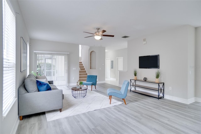 living room featuring stairs, a ceiling fan, baseboards, wood finished floors, and visible vents
