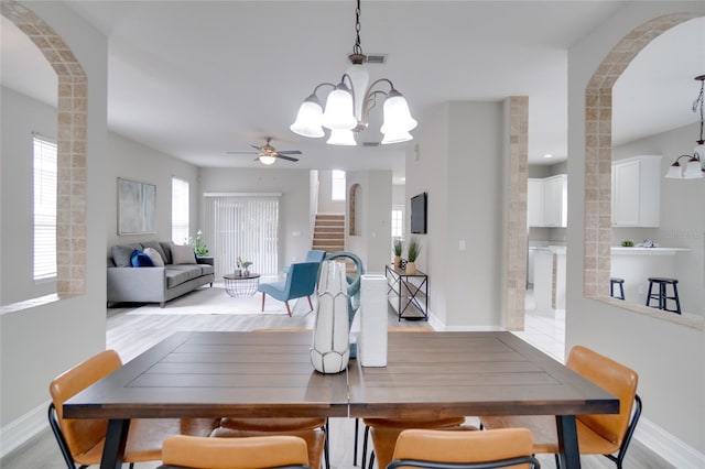 dining room featuring arched walkways, light wood-style flooring, and stairs