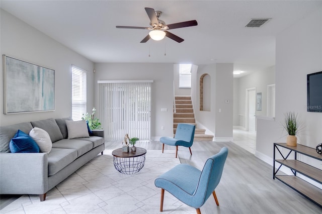 living room featuring stairway, plenty of natural light, ceiling fan, and visible vents