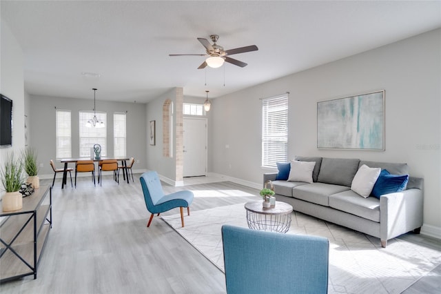 living room featuring ceiling fan with notable chandelier and light wood-type flooring